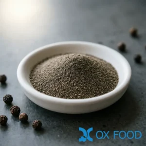 Hainan black pepper powder BPP-K36 dark grayish-brown fine powder in white ceramic sample dish on dark surface with whole black peppercorns scattered nearby