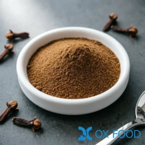 Clove powder CLO-D11 fine brown powder in white ceramic sample dish on dark surface with whole dried clove buds scattered nearby