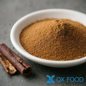 Cassia powder CP-B04 fine brown powder in white ceramic sample dish on dark surface with cassia bark pieces scattered nearby